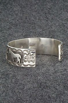 This sterling silver bracelet featuring horses was made by Navajo silversmith Preston Kinsel. The back is signed K and stamped sterling.Size: 5 5/8" (will fit up to a 6 7/8" wrist)Gap: 1 1/4"Width: 3/4"Free shipping on all orders! We ship with USPS and always include tracking. All orders ship within a day of payment.Returns are accepted up to 30 days after you receive your order. Just send us a message. Our shop offers cash back or store credit. The item must be returned in new condition. Western Sterling Silver Adjustable Bracelet Stamped 925, Adjustable Sterling Silver Western Bracelet, Adjustable Western Sterling Silver Bracelet, Western Style Adjustable Sterling Silver Bracelet, Silver Horse Design Bracelet Jewelry, Silver Horse Design Jewelry Bracelet, Silver Western Style Bracelet, Western Style Silver Bracelet For Gift, Western Style Silver Bracelets For Gift