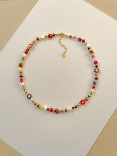 This necklace features cream, red, orange, mustard, matte transparent brown, and 24k gold plated seed beads. It also contains cream, green, purple, and orange crystal beads. As well as freshwater pearls, Amethyst, African Jade, sandstone, carnelian, agate, and copper spacer beads. Length: 16" inches Seed Bead Size: 11/0, 6/0, 2mm, 4mm, 6mm Adjustable: Each necklace has a 2" 18k gold filled lobster clasp extender Strung on: Non-Stretchy Beading Thread Please note: gemstones vary in color making each necklace a little unique! Soft Autumn Jewelry, Beaded Flower Necklace, Necklace Colorful, Orange Crystals, Pretty Necklaces, Funky Jewelry, Fall Jewelry, Seed Bead Necklace, Colourful Necklace