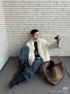 a woman sitting on the ground with a purse and cell phone in her hand while holding a camera