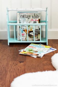 a magazine rack sitting on top of a wooden floor next to a white sheepskin rug