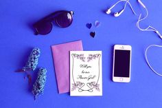 an assortment of personal items laid out on a blue surface with sunglasses, cell phone and notepad