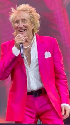 a man in a pink suit singing into a microphone