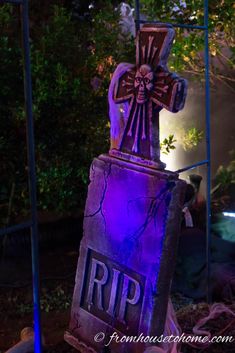 an old tombstone with a cross on it in the middle of a yard at night