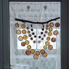 a window decorated with oranges and star shaped decorations in front of a lace curtain