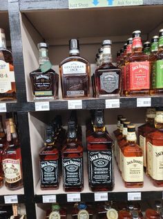 many different types of liquor are on display in a store shelf with labels for each bottle