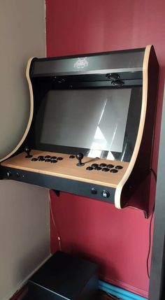 an old fashioned arcade machine in the corner of a room with a red wall behind it