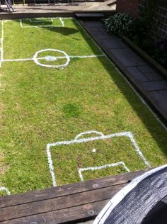 someone is sitting on the grass in front of a soccer field with chalk drawings drawn on it