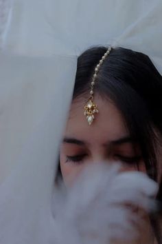 a woman wearing a head piece with pearls and beads on it's forehead is looking down