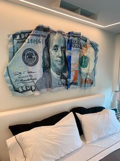 a bed that has some money on the wall above it and pillows in front of it