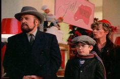 two adults and a child standing next to each other in front of a christmas tree