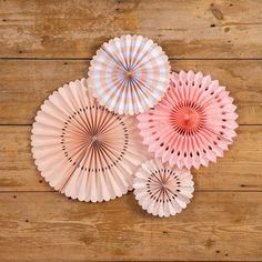 three pink paper fans on a wooden surface