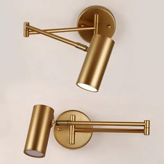 two brass colored wall lights with one light on each side and the other off to the side