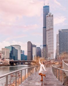 a woman standing on a wooden bridge in front of a cityscape with skyscrapers