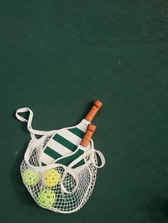 a tennis racquet and ball in a net on the court with green background