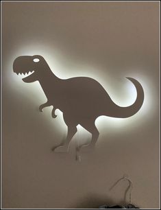 a light that is on the side of a wall with a dinosaur silhouette in it