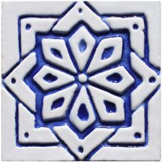 a blue and white tile with an intricate design on it's side, in the shape of a snowflake