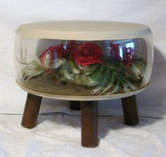 a vase with flowers in it sitting on top of a wooden stand