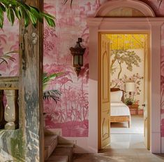 an open door leading to a bedroom with pink walls and palm trees on the wall