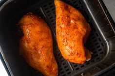 two pieces of chicken sitting in an air fryer