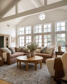 a living room filled with lots of furniture and large windows in the wall behind it