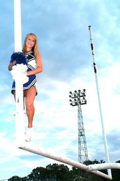 a cheerleader is standing on the pole with her pom poms