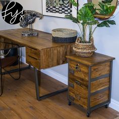 a wooden desk sitting next to a potted plant on top of a wooden table