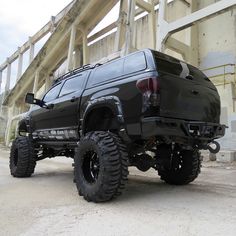 a large black truck parked in front of a bridge