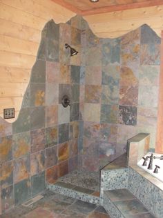 a bathroom with stone walls and tile flooring, including a shower stall in the corner