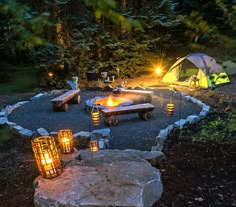 an outdoor fire pit in the middle of a forest at night with lights on it