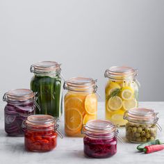 several jars filled with different types of vegetables and fruits next to each other on a table