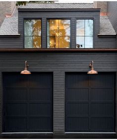 two black garage doors are open in front of a house