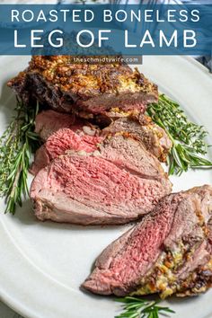 roasted boneless leg of lamb on a white plate with rosemary garnish