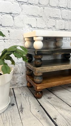 a potted plant sitting on top of a wooden stand next to a white brick wall