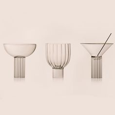 three glass bowls and one bowl with a straw sticking out of the top, on a white background