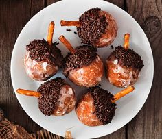 a white plate topped with donuts covered in chocolate and sprinkles on top of a wooden table