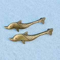 two gold colored fish figurines sitting on a blue surface