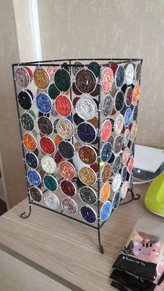 a wooden table topped with a metal rack filled with lots of different colored paint bottles