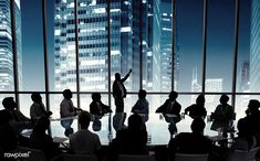 a group of people sitting around a conference table in front of tall buildings at night