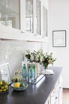 a kitchen counter topped with lots of bottles and fruit