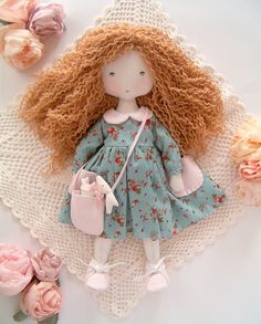 a doll is sitting on a doily with flowers around it and holding a purse