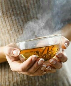 a woman holding a cup of tea with steam rising from it