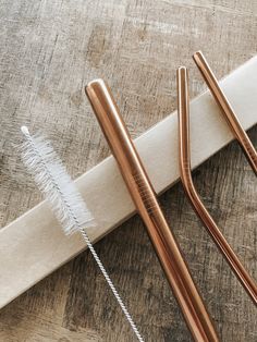 three metal straws sitting on top of a wooden table