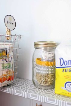 some food is sitting on a shelf next to a bag of cereal and a glass jar