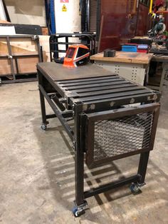 a metal table sitting on top of a wooden floor next to a machine tool box