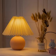 a yellow lamp sitting on top of a table next to a vase filled with flowers