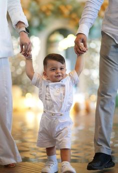 a little boy holding the hand of his mother