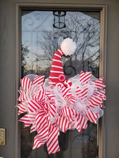 a red and white striped christmas wreath on the front door with a santa's hat