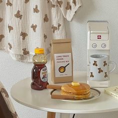 pancakes, butter and syrup are on a table next to a toaster with thermos