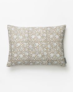 an embroidered pillow on a white wall with a brown and white flower pattern in the middle