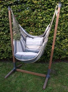 a hammock hanging in front of a hedge with two pillows on the bottom